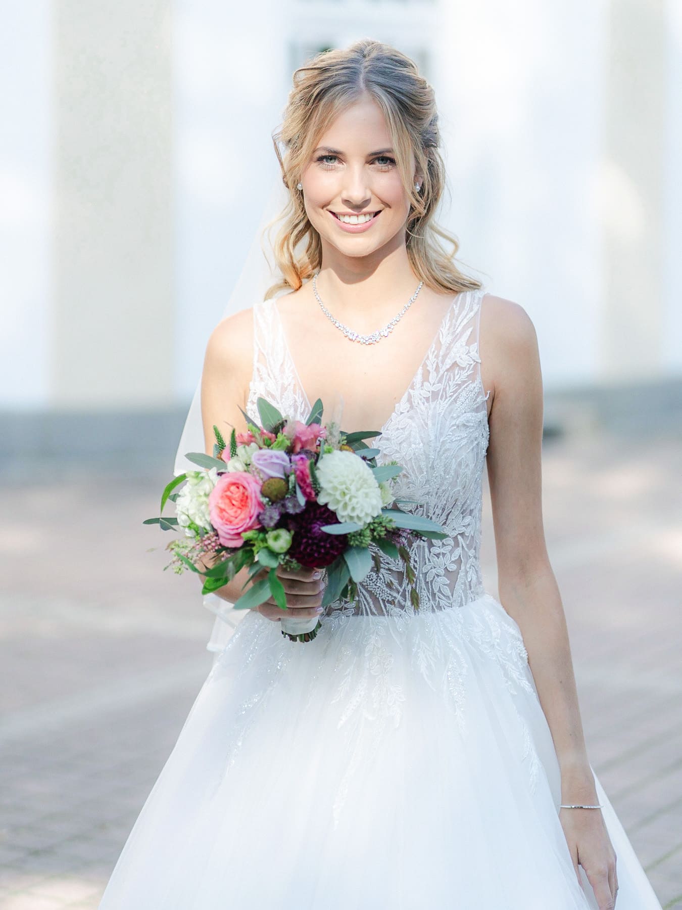 Braut lacht im Brautkleid mit Hochzeitsstrauß