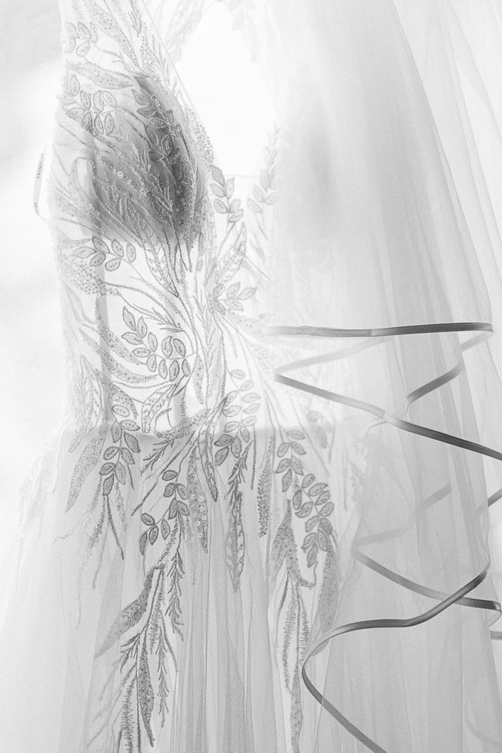 Brautkleid verziert vor Fenster schwarz weiß