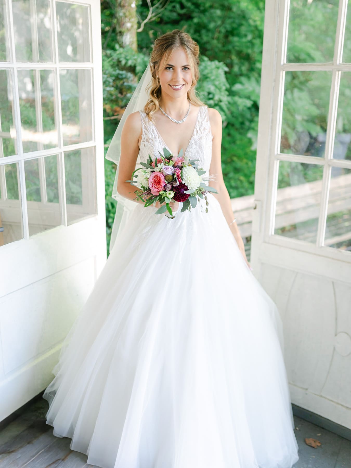 Braut lacht im Brautkleid mit Hochzeitsstrauß
